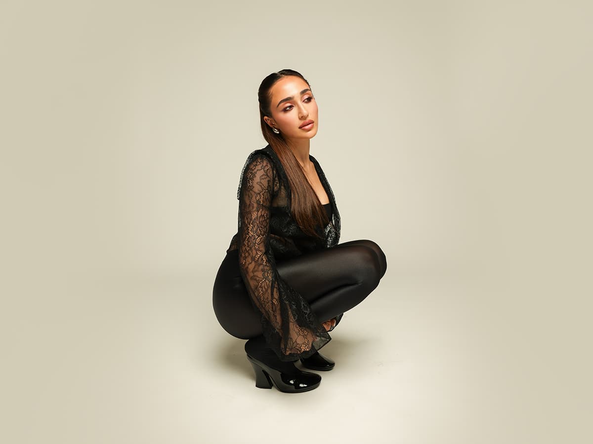 Sara Charif posing in black lace against a warm neutral background